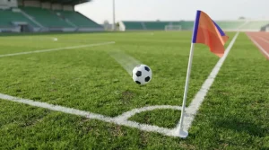 Fußball im Flug vor einem Tor auf einem beleuchteten Spielfeld